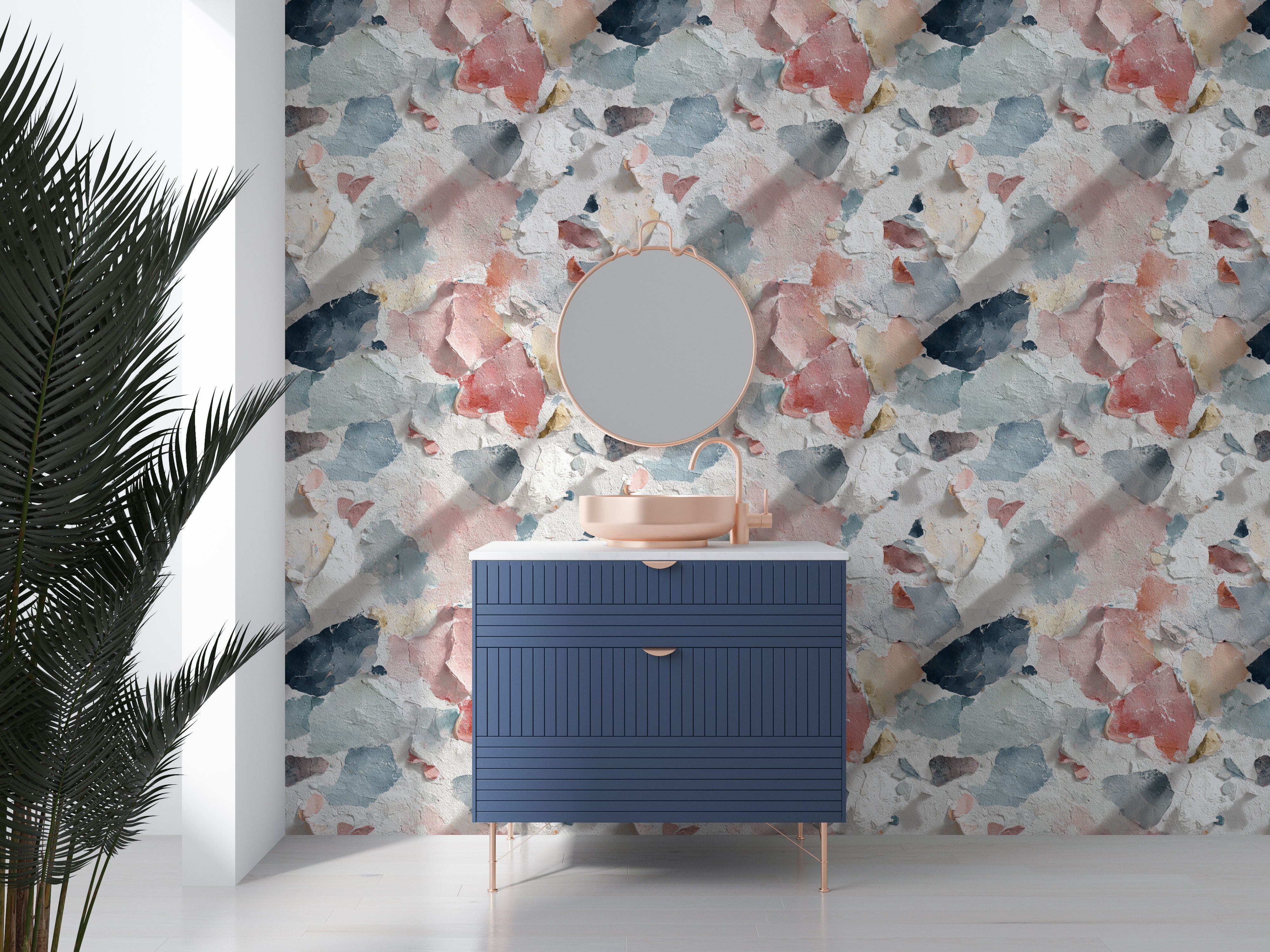 Distressed paint wallpaper in coral blue cream and navy decorates a bathroom vanity with round mirror and peach sink