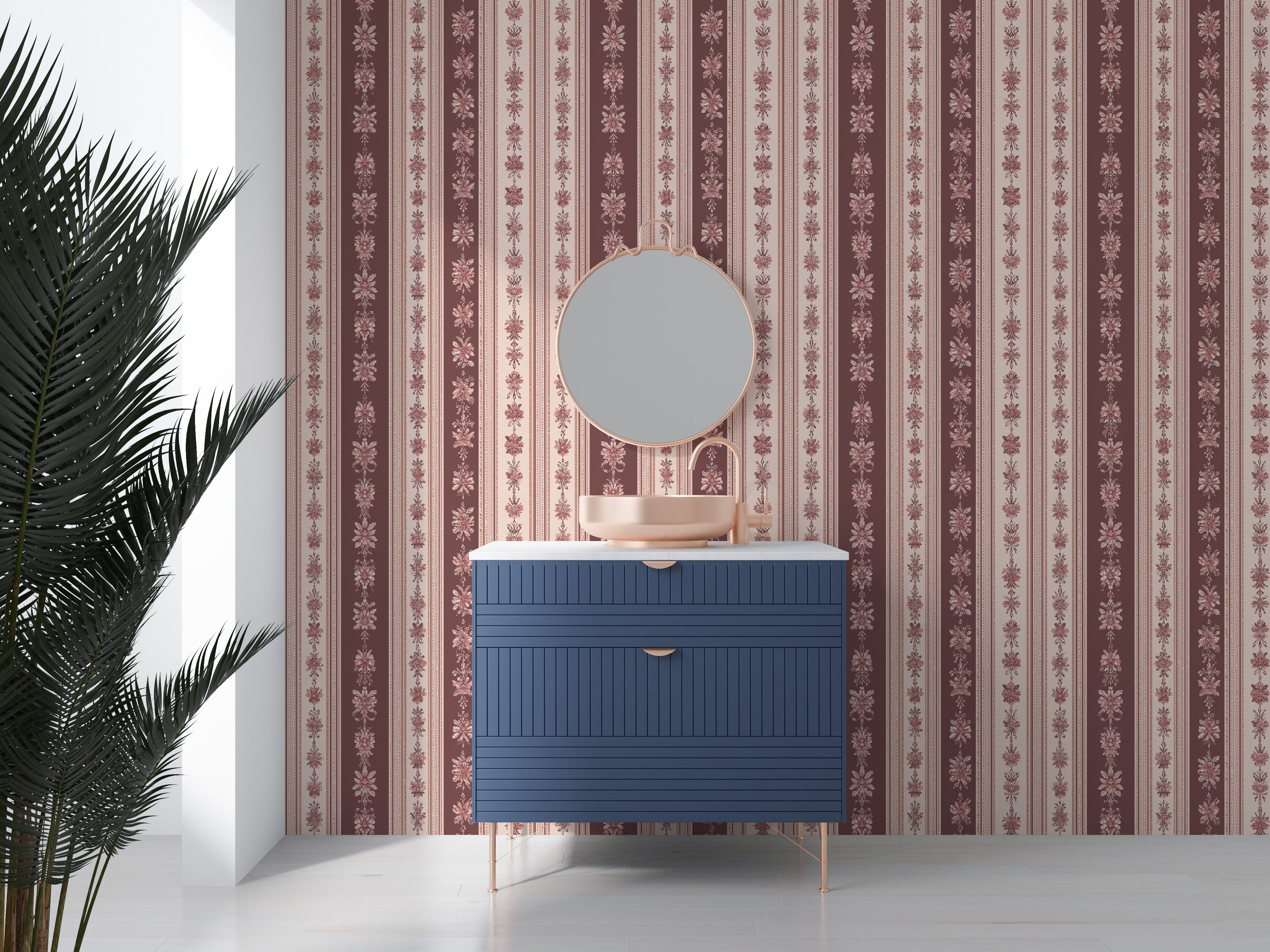 A bathroom vanity with a blue textured vanity, round mirror, beige vessel sink, and vintage floral striped wallpaper