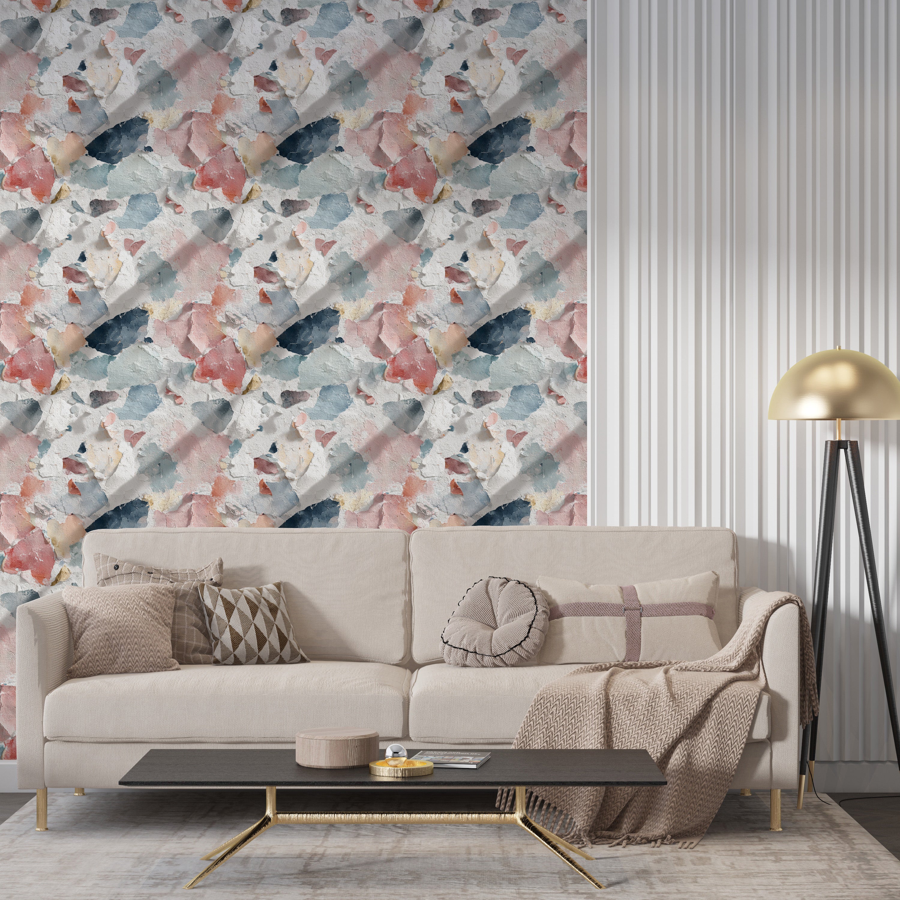 Distressed paint wallpaper in coral blue cream and navy tones on a living room wall with a beige sofa and modern gold lamp